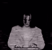 a black and white image of a person in a dark room with a blurred background .
