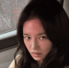 a woman with a red spot on her forehead is looking at the camera