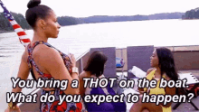 a group of women are sitting on a boat in the water and one of them is asking another woman what she expects to happen .