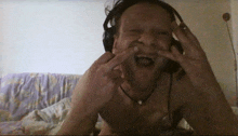 a shirtless man wearing headphones making a face