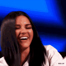 a close up of a woman laughing with her hair blowing in the wind .