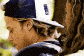 a man wearing a trucker hat is looking at a woman .