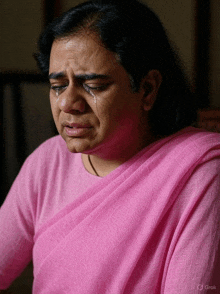 a woman in a pink sweater is crying with a tear running down her face