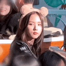 a woman wearing a teddy bear headband is sitting in front of a crowd of people .