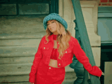 a woman wearing a red jacket and a blue hat is standing on a set of stairs
