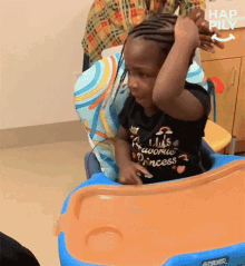 a little girl is sitting in a high chair with her hair in braids .