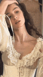 a woman is wearing a white lace corset and ruffled sleeves