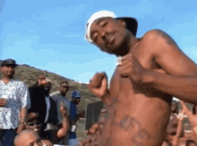 a shirtless man with a tattoo on his stomach is standing in front of a crowd of men .