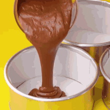 chocolate batter is being poured into a pan on a yellow surface