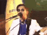a man is singing into a microphone while playing a guitar .