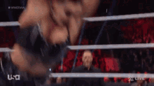 a wrestling match is taking place in a ring with a referee .
