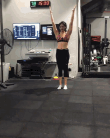 a woman is jumping in front of a digital clock that says 15:08