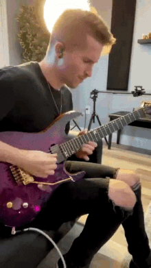 a man is playing a purple electric guitar
