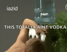 a man is drinking water from a water cooler with the words this totally ain t vodka above him .