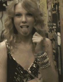a woman sticking her tongue out while wearing a black top and bracelets