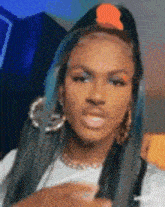 a woman with blue hair and earrings is wearing a white shirt and a black vest .