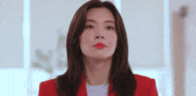 a woman in a red jacket is looking at the camera with a serious look on her face .