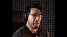 a man wearing headphones and glasses is making a surprised face .