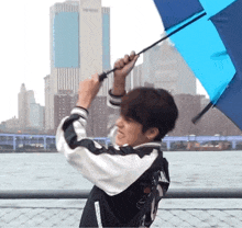 a man is holding a blue umbrella in front of a skyline