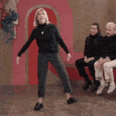 a woman in a black turtleneck is dancing in front of a pink heart