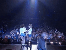a man playing a guitar and a woman hugging on stage
