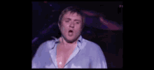 a man in a blue shirt is standing in a dark room .