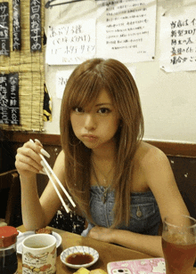 a woman is sitting at a table with chopsticks and a cup that says ' chicken ' on it