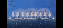 a group of women in white dresses are dancing on stage