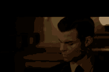 a man in a suit and tie is looking down at something in a dark room .