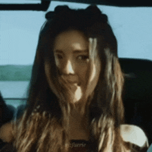 a woman with long hair is sitting in the back seat of a car making a funny face .
