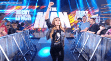 a woman is standing in a ring with her fist in the air in front of a crowd .