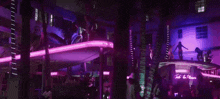 a group of people are dancing in a club with purple lights and palm trees .