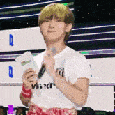 a young man is holding a microphone and a piece of paper .