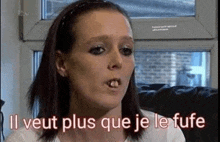 a woman is sitting in front of a window with the words `` il veut plus que je le fufe '' above her .