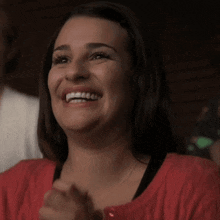 a woman in a red sweater is laughing and clapping her hands