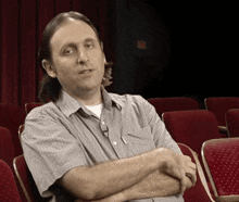 a man sitting in an auditorium with his arms crossed