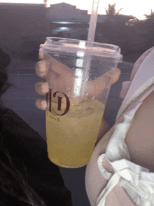 a person is holding a cup with a straw and the letter d on it