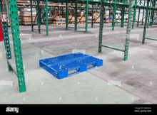 a blue plastic pallet is sitting on the floor of an empty warehouse