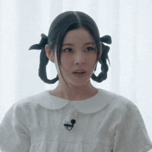 a woman wearing a white shirt with a microphone on her neck