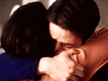a man is kissing a woman on the cheek while they are hugging each other .