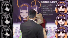 a man in a suit is standing in front of a screen with a song list on it .