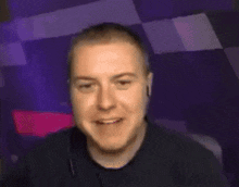 a man wearing headphones is smiling in front of a purple background .