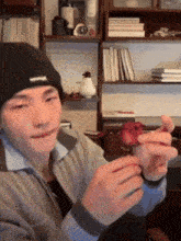 a man wearing a black beanie holds a piece of fruit in his hands