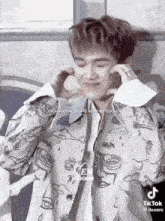 a young man is making a heart shape with his hands while wearing a jacket .