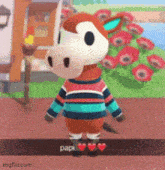 a donkey wearing a striped sweater is standing in front of flowers and a house .