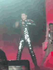 a man in a shiny suit is dancing on stage