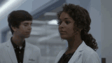a woman in a lab coat stands next to a man