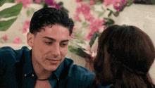a man and a woman are looking at each other with pink flowers in the background