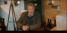 a man sits at a desk with a glass of beer in his hand