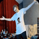 a man wearing a white shirt with a picture of a man on it is dancing in a room .